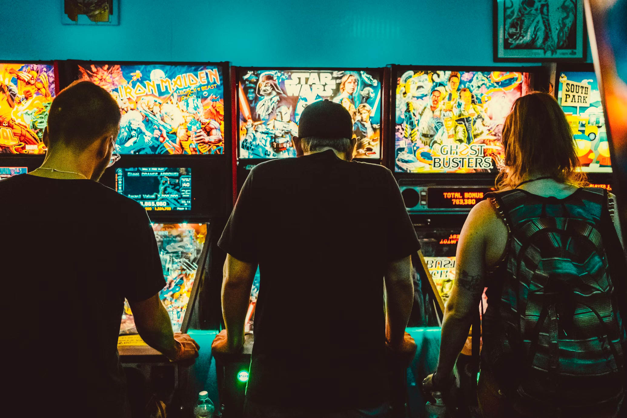 Three people playing pinball.