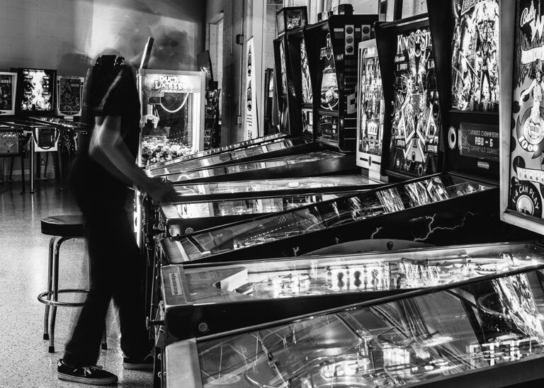 Black and white photo of a man playing pinball